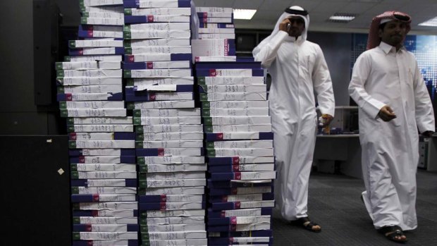 Employees walk past stacks of tapes in the studio of Qatar-based satellite news channel Al Jazeera.