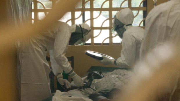 Dr Kent Brantly, left, and other health workers care for Ebola patients in Monrovia, Liberia. Dr Brantly now has the virus.