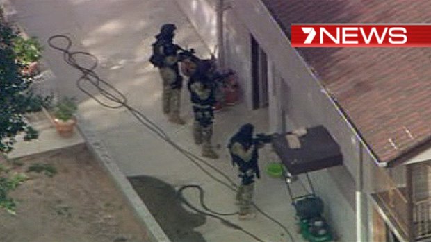 A SERT team surrounding an Algester house earlier where police at one stage believed fugitives were hiding. Screengrab from Channel 7.