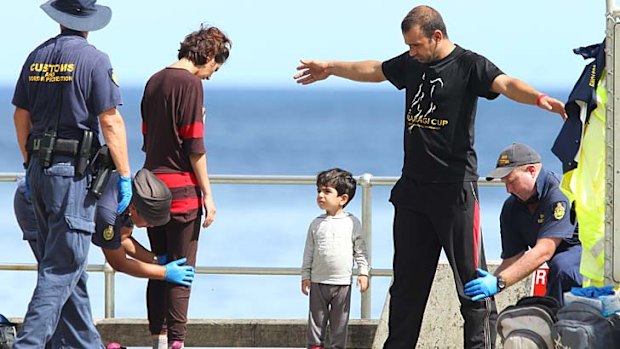 A family seeking asylum are processed by Customs and immigration department officials after their arrival at Flying Fish Cove, Christmas Island.