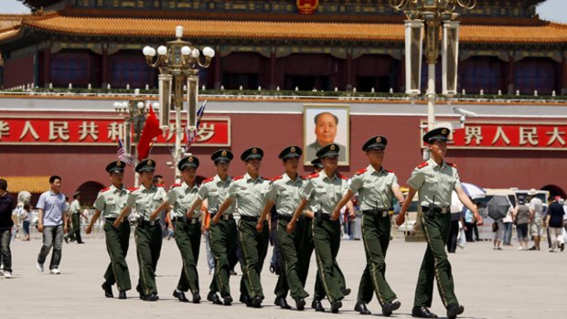 Policemen march in front of the giant portrait of Chairman Mao Zedong in Tiananmen Square. 