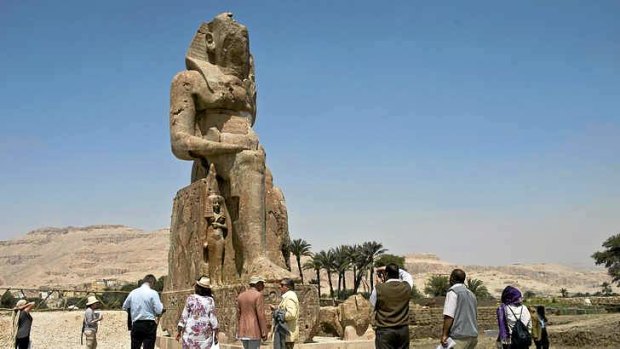 Tourists and journalists stand next to a newly displayed statue of pharaoh Amenhotep III and his wife Tiye (Down) in Egypt's temple city of Luxor.