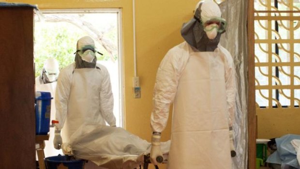Two orderlies in protective clothing carry a body at an Ebola isolation ward.