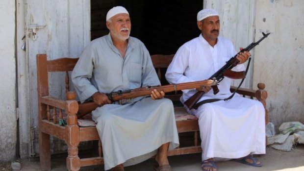 Iraqi men sit with their weapons in the Iraqi town of Jdaideh in  Diyala province on June 14 after they volunteered to join the fight following the call to arms by Shiite cleric Grand Ayatollah Ali al-Sistani.