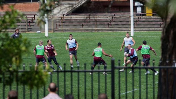 Behind ‘‘closed’’ doors ... members of the media and general public watch through the fence as Manly go through their paces yesterday.