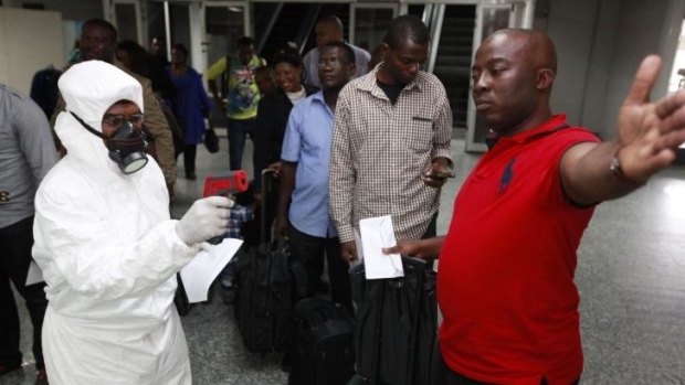 A Nigerian port health official uses a thermometer on a passengers at the arrivals hall of Murtala Muhammed International Airport in Lagos, Nigeria.
