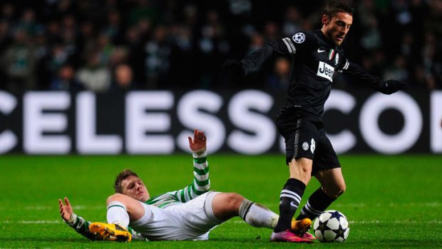 Claudio Marchisio of Juventus (right) skips the challenge of Kris Commons of Celtic  during the Champions League round-of-16 match between Celtic and Juventus at Celtic Park Stadium.