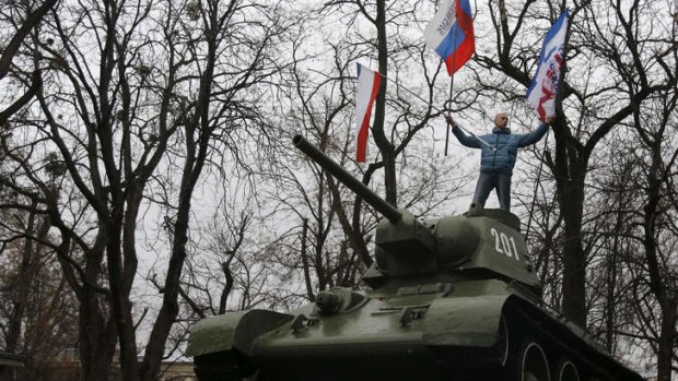 A Pro-Russian demonstrator waves Russian and Crimea flags from an old Soviet Army tank  in Simferopol.