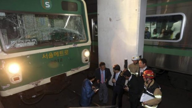 Investigators inspect the site where two subway trains collided in Seoul.