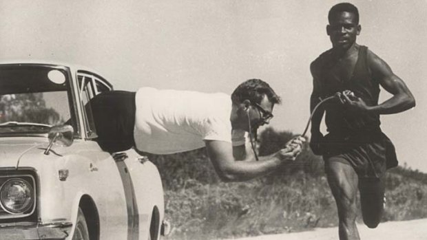 A driven coach ... Dr John Cheffers hangs out of a car to take the heartbeat of Rhodesia's Olympic marathon hope in 1968, John Shava.