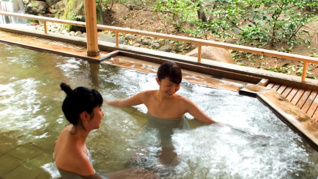 Two young women bathing in onsen in Japan. Some onsens no longer require bathers to be nude, particularly those that accommodate foreign visitors. 