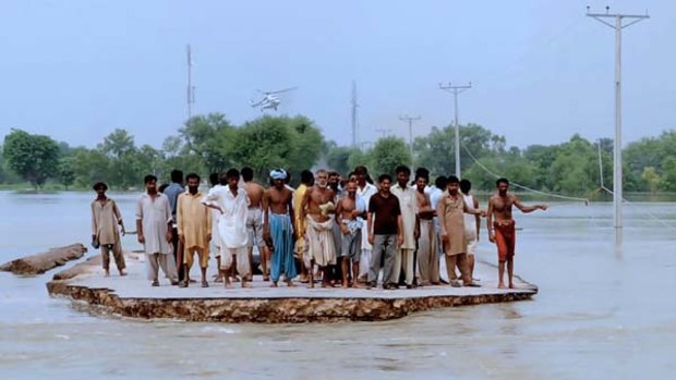 Pakistani survivors gather as they await rescue at a flooded area of Khangarh.