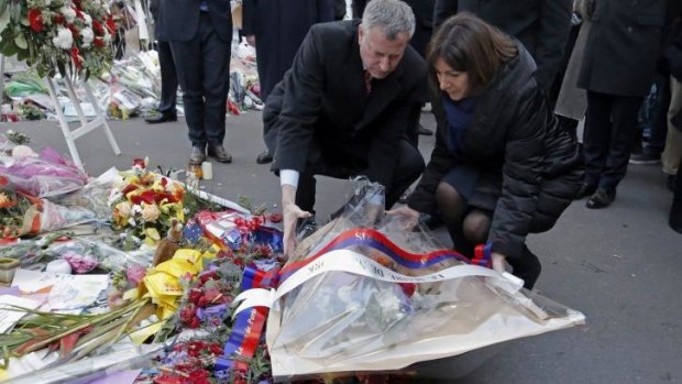 New York City Mayor Bill de Blasio, left, and Paris mayor Anne Hidalgo, right, lay a wreath of flowers at the site of the <i>Charlie Hebdo</i> newspaper attack, in Paris.