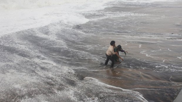 A man carries his wife to safety after a wave knocked her over on a beach at Gopalpur in the eastern Indian state of Odisha.