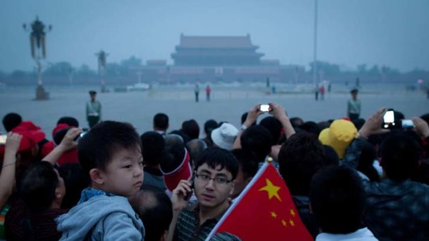Generational ties ... a child waves a flag at the national flag raising ceremon in Tiananmen Square.