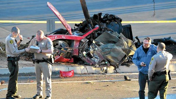 Sheriff deputies work near the wreckage of a Porsche sports car that crashed into a light pole.