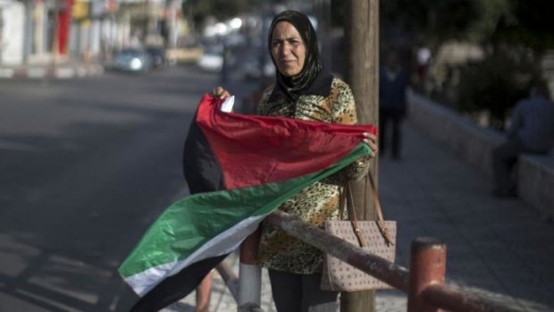 A Palestinian woman waves the national flag as she celebrates the agreement to form a unity government in Gaza.