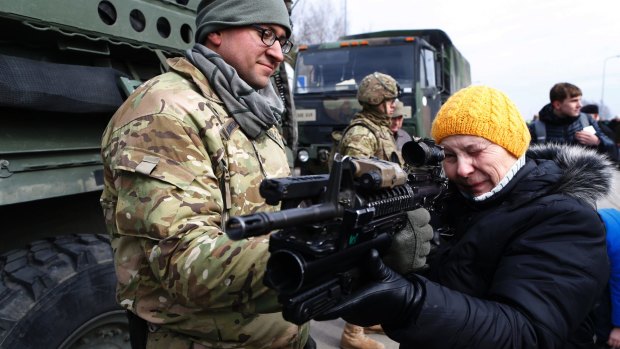 A US soldier demonstrating the uses of his weapon to shows a gun to a Lithuanian woman during military exercises in Lithuania in March. 