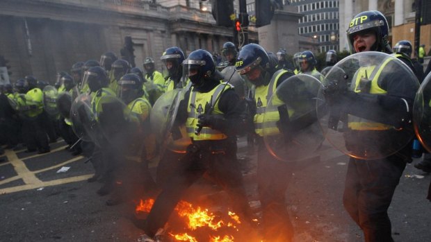 Police in riot gear advance through fires set by demonstrators during anti-G20 protests in London, 2009.