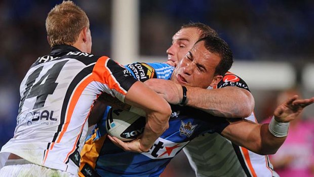 Toppled Titan . . . the Gold Coast's Bodene Thompson tackled by two Wests Tigers players.