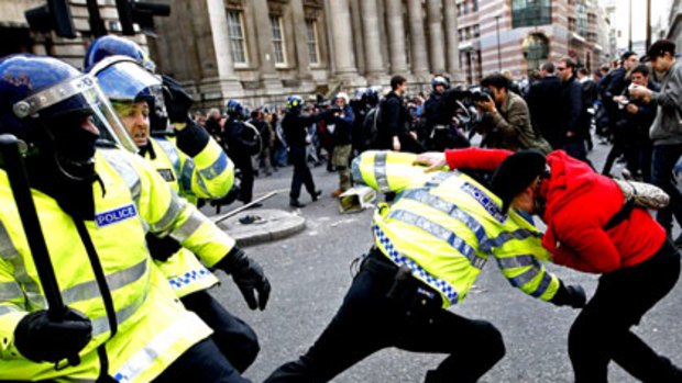 A demonstrator scuffles with police during protests outside the Bank of England into London.