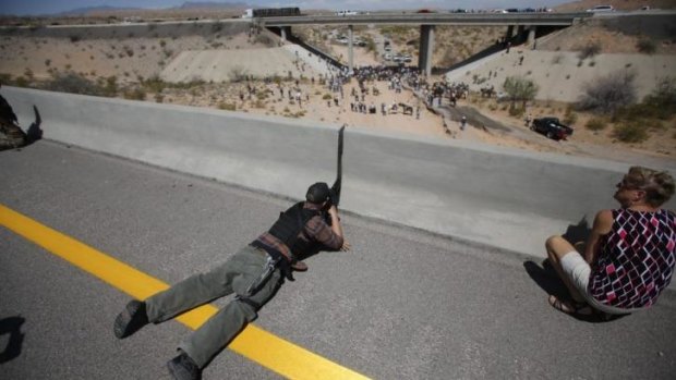 Supporter of grazing rights ... Eric Parker aims his weapon from a bridge as protesters gather by the Bureau of Land Management's base camp near Bunkerville, Nevada during the recent standoff.