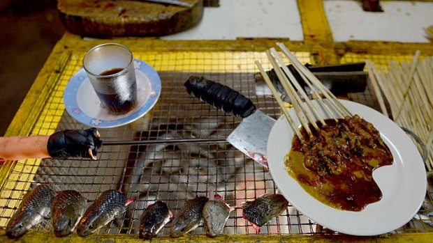 Cobra satay sticks, and heads, at a street stall serving a variety of foods including cobra and lizards in Jakarta.