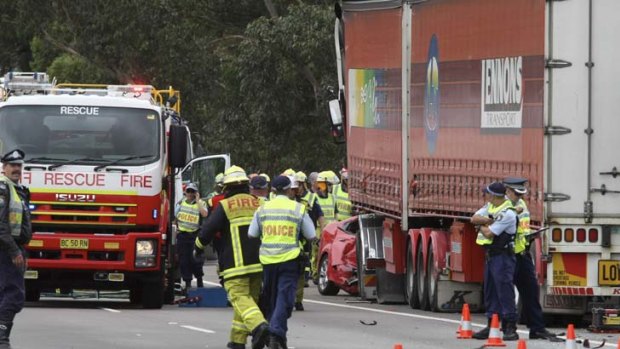 Loss &#8230; police and rescue staff investigate a crash on the Hume Highway, south of Sydney, after a semi-trailer collided with a red Ford, killing all three occupants.