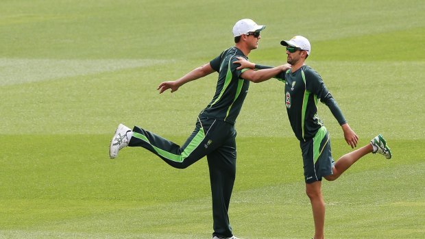 Josh Hazelwood stretches with Nathan Lyon during an Australian nets session.
