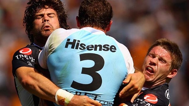 Tiger hug .... Sharks centre Ben Pomery is tackled by Matt Bell and Chris Lawrence of the Wests Tigers.