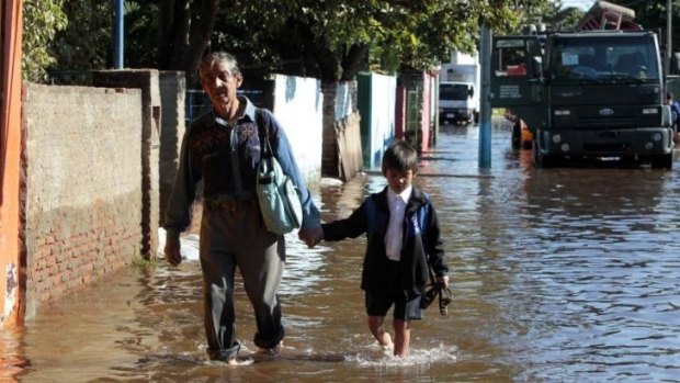 A man and his grandson walks through floodwaters near the Paraguay River in Asuncion, Paraguay.  Brazil's southern state of Parana has also been hit by heavy flooding.