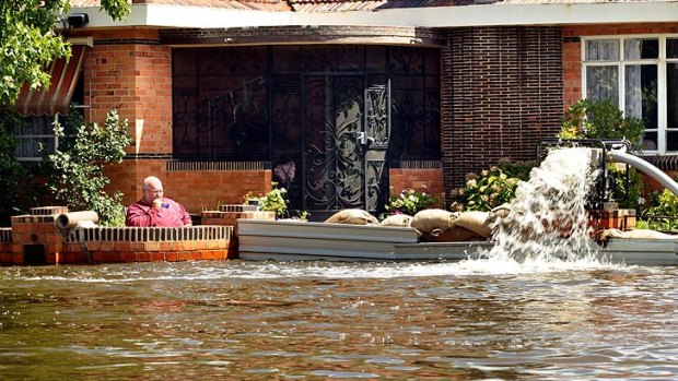 A Numurkah resident tries to protect his home with sandbags and a pump as water rises around him.