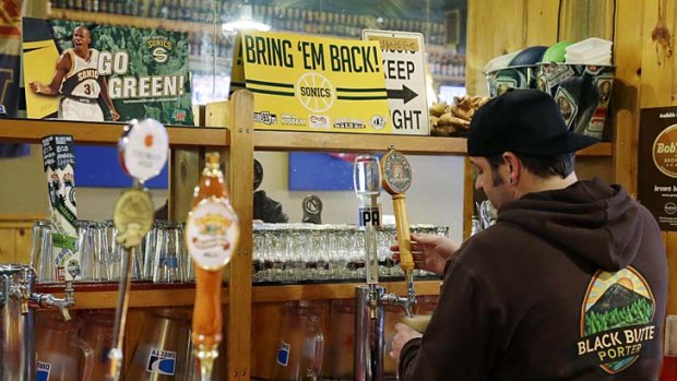 Christian Adametz, owner of Floyd's Place in Seattle, pours a beer for a customer next to a sign that reads "Bring 'Em Back!" in reference to the Seattle SuperSonics NBA basketball team.