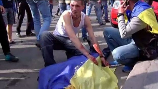 This still grabbed on TV images released by INTER, shows a man covering the bloodied body of a man with an Ukrainian flag during a demonstration in Odessa.