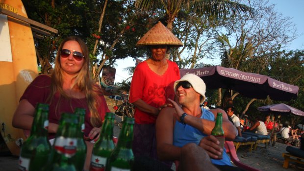 An Australian couple drinks beer while watching the sunset at Legian Beach in Bali.