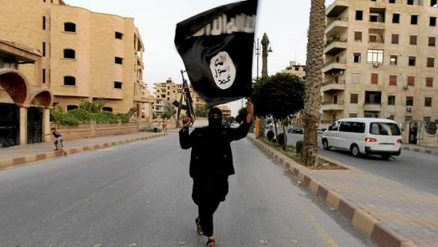 A member loyal to the Islamic State in Iraq and the Levant waves an ISIL flag in Raqqa.