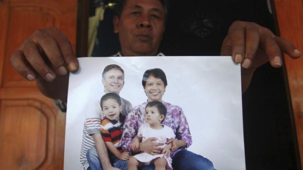 Widi Yuwono, the brother of Yuli Hastini, right, shows her sister's family portrait with her Dutch husband John Paulissen and their two children Arjuna and Sri