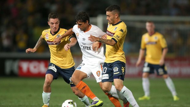 Thomas Broich of the Roar attempts to ward off Storm Roux and Anthony Caceres of the Mariners.