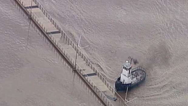 Peter Fenton's tugboat guides a 150-metre section of the Floating Riverwalk out of harm's way during the Brisbane flood.