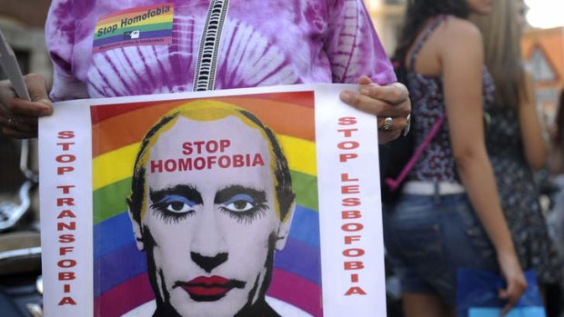 A demonstrator holds a poster depicting Russian President Vladimir Putin with make-up as he protests against homophobia and repression against gays in Russia, outside the Ministry of Foreign Affairs and Cooperation in Madrid.