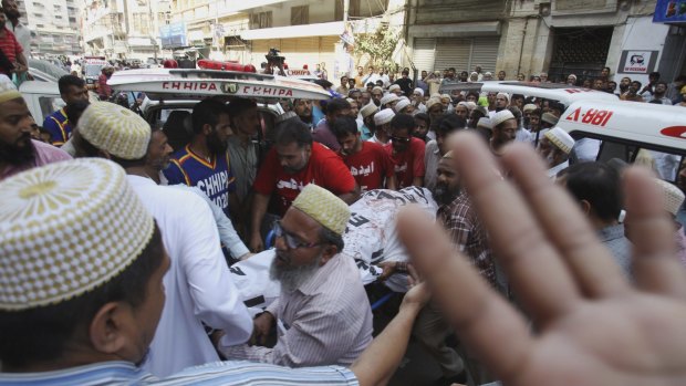 Victims of the Karachi bombing carried to ambulances on Friday.