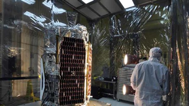 In a clean room at Vandenberg Air Force Base's processing facility in California, a technician conducts a solar array illumination test on NASA's NuSTAR spacecraft.