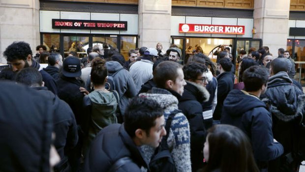 People wait for the opening of a  Burger King store at Saint-Lazare railway station in Paris.