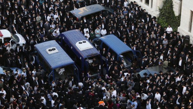 Ultra-Orthodox Jews mourn over the bodies of three of the victims.