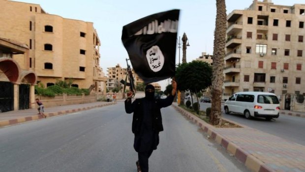 A member loyal to the Islamic State in Iraq waves an ISIL flag in Raqqa.