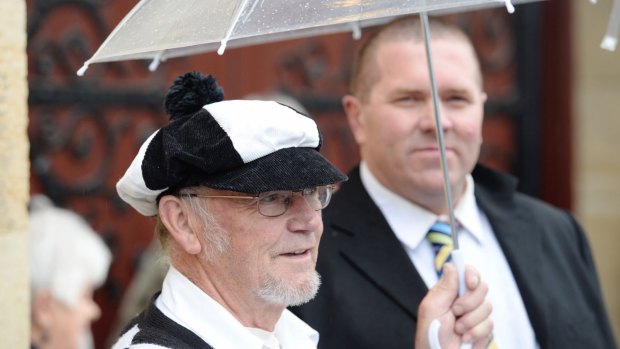 Magpie fan Albert Thyssen shows his colours as rain falls outside the cathedral.