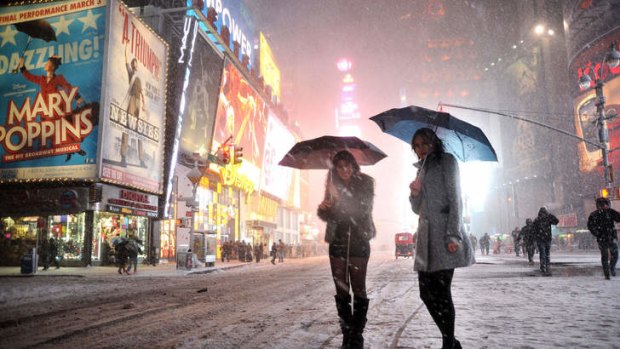 Two women look for a taxi in the snow during a storm in Times Square in New York.