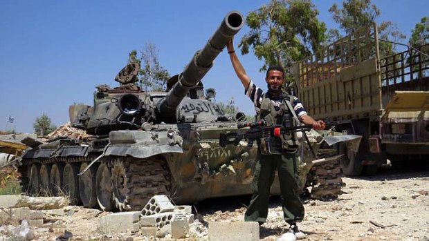 A rebel fighter with a tank reportedly confiscated from an army barracks. The US has sharply toughened its line on Syria, promising the rebels weapons for the first time.