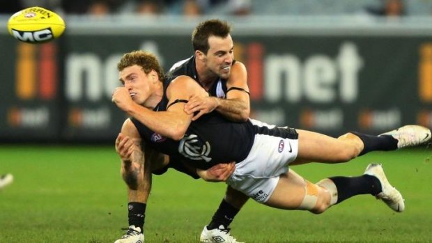 Carlton's Mitch Robinson handballs as he is grabbed by Collingwood's Steele Sidebottom.