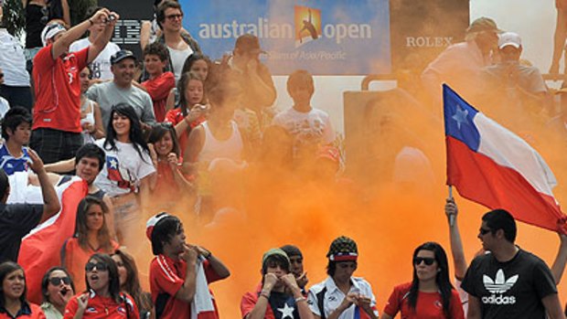 Chilean fans wave their country's flag as flares are set off in the crowd on court three.